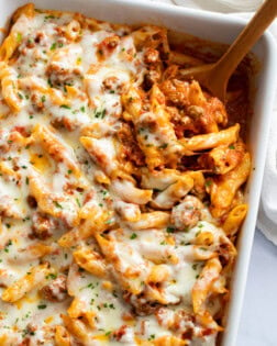 Ground Beef Casserole in a white baking dish with a wooden spoon scooping it out.