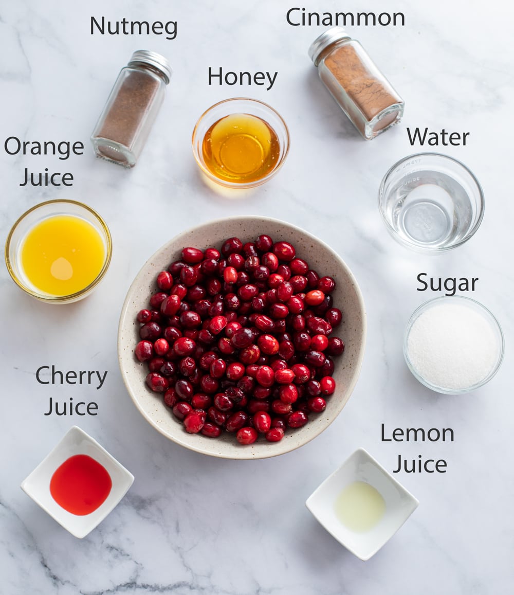 Ingredients for making Cranberry Sauce on a white surface with labels.