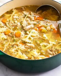 Turkey Soup in a green soup pot with vegetables, turkey, and pasta.