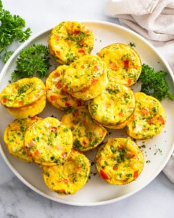 Egg Muffins on a white plate with parsley and colorful fillings.