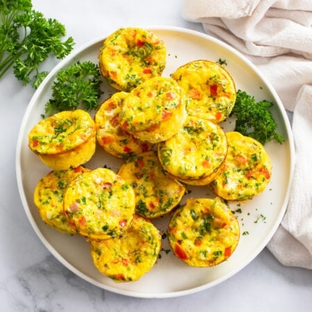 Egg Muffins on a white plate with parsley and colorful fillings.