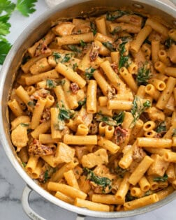 Marry Me Chicken in a skillet with a tomato cream sauce, sun-dried tomatoes, and spinach.