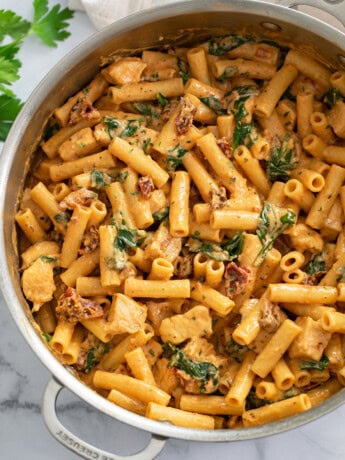 Marry Me Chicken in a skillet with a tomato cream sauce, sun-dried tomatoes, and spinach.