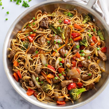 Beef Lo Mein in a skillet with vegetables and brown sauce.