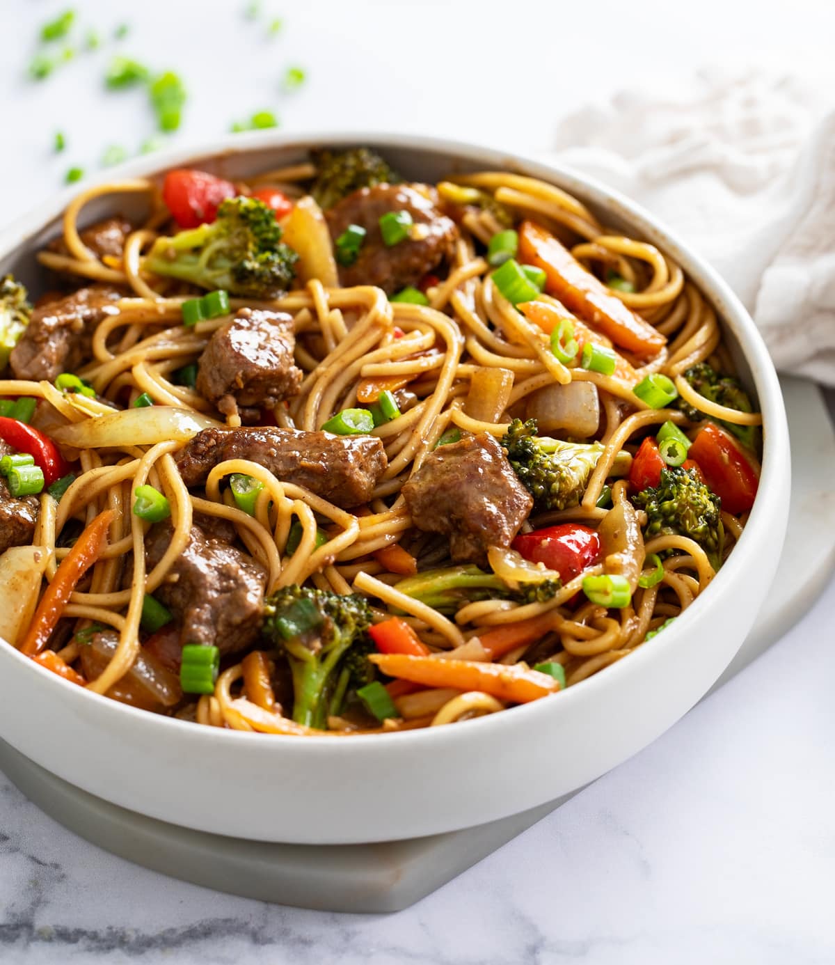 Beef Lo Mein in white bowl with noodles, beef, vegetables, and sauce.