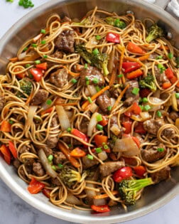 Beef Lo Mein in a skillet with beef, noodles, and vegetables in sauce.