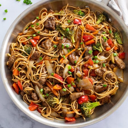 Beef Lo Mein in a skillet with beef, noodles, and vegetables in sauce.