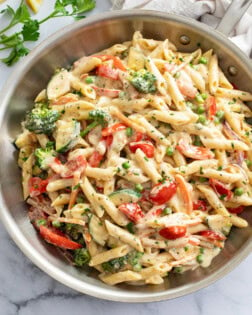 Pasta primavera in a skillet with a cream sauce and vegetables.