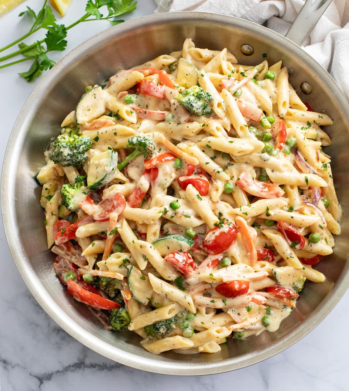 Pasta primavera in a skillet with a cream sauce and vegetables.