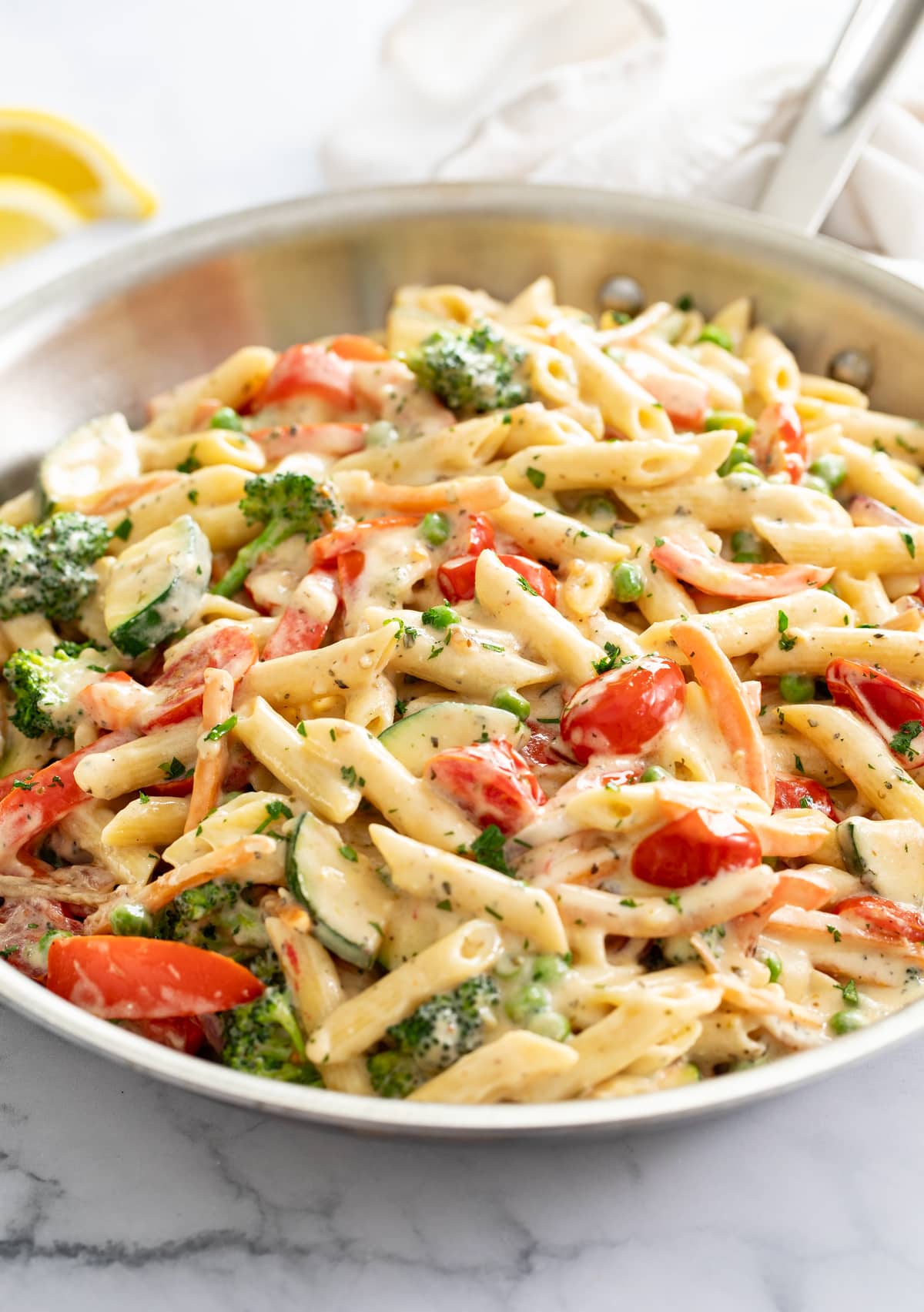 Pasta Primavera in a skillet with penne in a cream sauce with colorful vegetables.