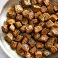 Steak Bites in a skillet with chopped parsley on top.