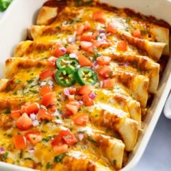 Chicken Enchiladas in a casserole dish with cheese and toppings on top.