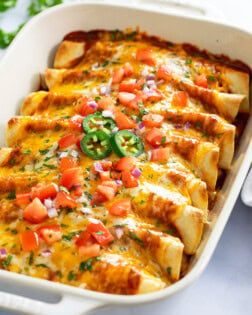 Chicken Enchiladas in a casserole dish with cheese and toppings on top.