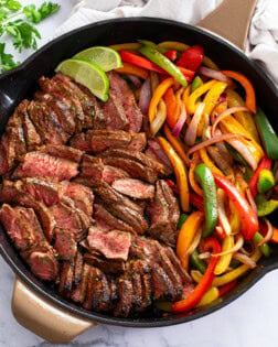 Steak Fajitas in a skillet with seasoned steak, onions, and peppers.