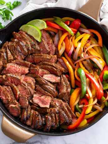 Steak Fajitas in a skillet with seasoned steak, onions, and peppers.