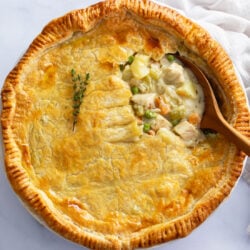 Overhead view of Chicken Pot Pie in a pie pan with a wooden spoon scooping it up.
