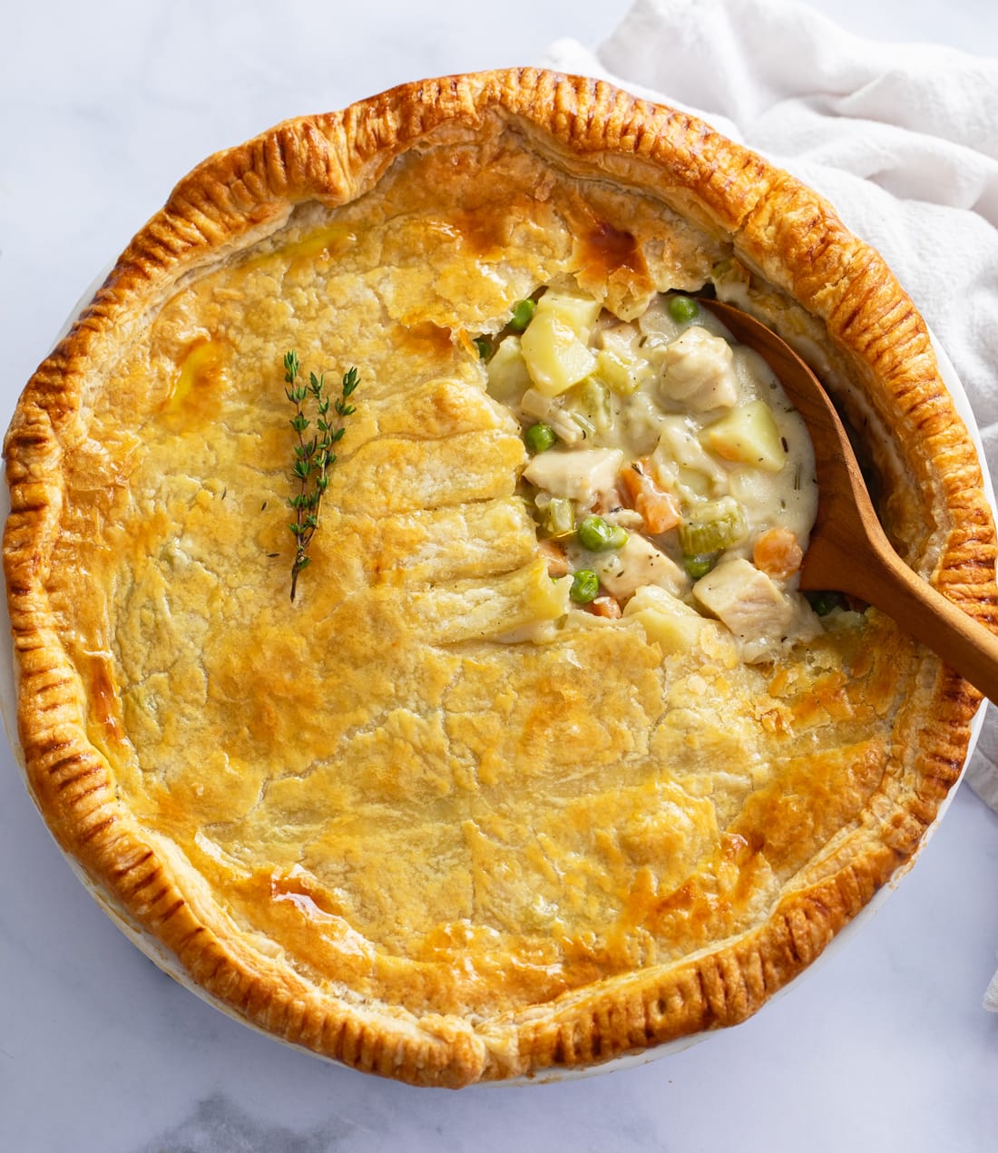 Overhead view of Chicken Pot Pie in a pie pan with a wooden spoon scooping it up.