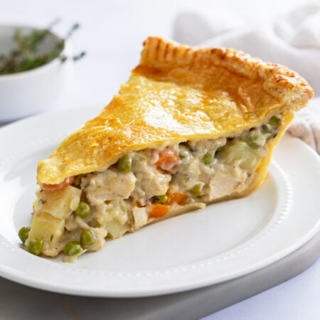 A thick slice of double crust Chicken Pot Pie with a creamy filling with chicken, potatoes, and vegetables.