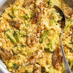 Chicken and Orzo in a creamy cheese sauce with broccoli in a skillet with a spoon on the side.