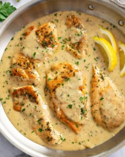 Garlic Parmesan Chicken in a skillet with sauce and fresh parsley on top.