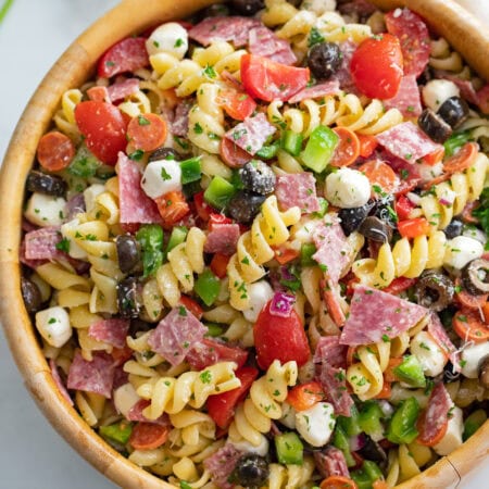 Italian Pasta Salad in a wooden bowl with meat, cheese, olives, and rotini pasta.