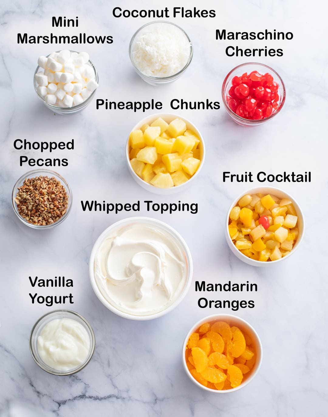 Ingredients for making Ambrosia Salad on a white surface with labels.