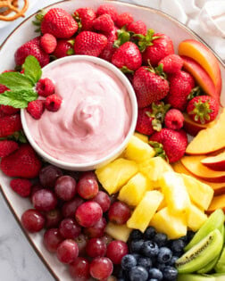 Overhead view of a platter of Fruit with Fruit Dip in a bowl on the side.