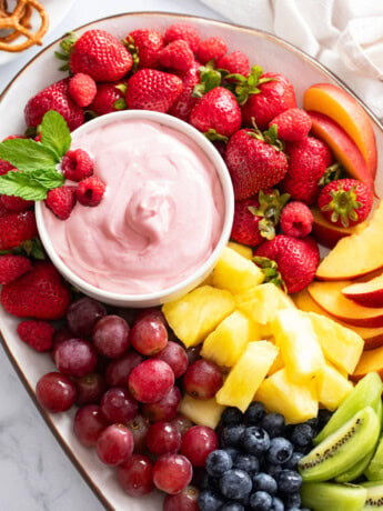 Overhead view of a platter of Fruit with Fruit Dip in a bowl on the side.