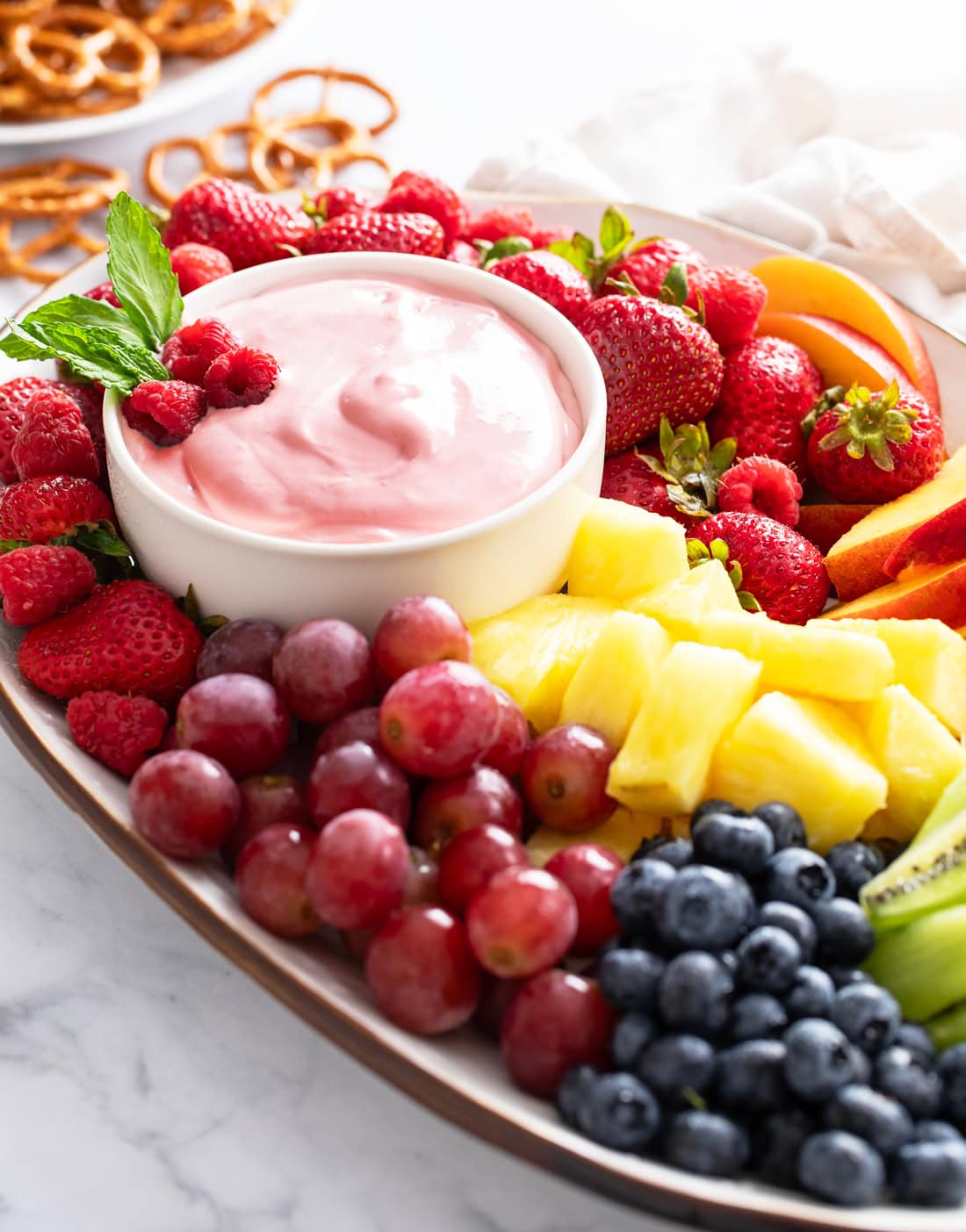 A bowl of Fruit Dip on a platter with a colorful fruit arrangement.