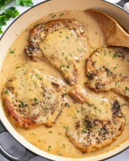 Garlic Parmesan Pork Chops in a skillet with a spoon on the side and parsley on top.