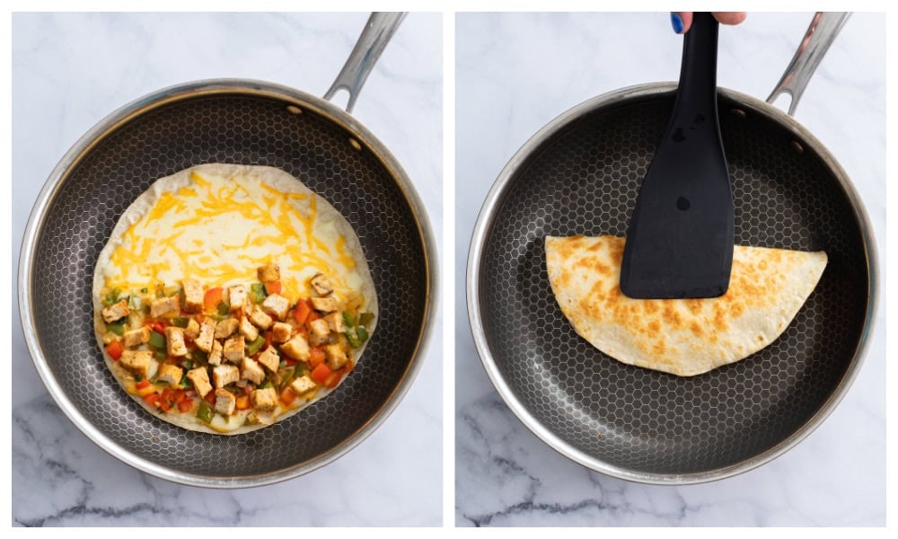 Folding a quesadilla with cheese, chicken, peppers, and onions in half in a skillet.