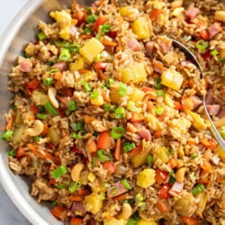 A skillet of Pineapple Fried Rice topped with green onions and cashews.