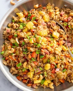 A skillet of Pineapple Fried Rice topped with green onions and cashews.