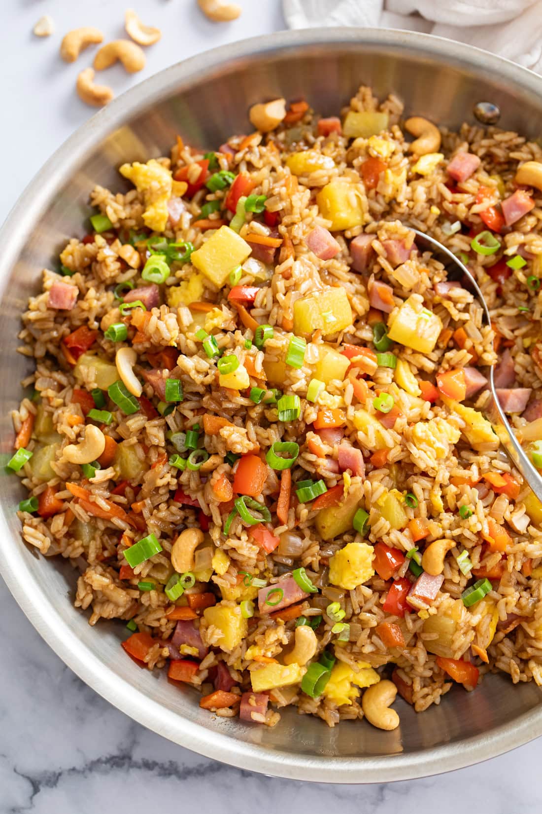 A skillet of Pineapple Fried Rice topped with green onions and cashews.