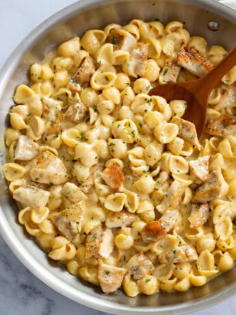 Chicken Mac and Cheese in a skillet with a wooden spoon.