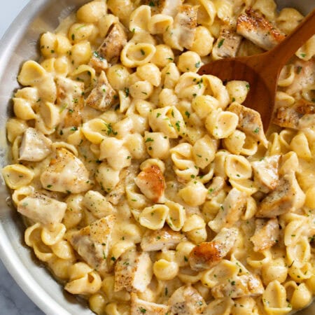 Chicken Mac and Cheese in a skillet with a wooden spoon.