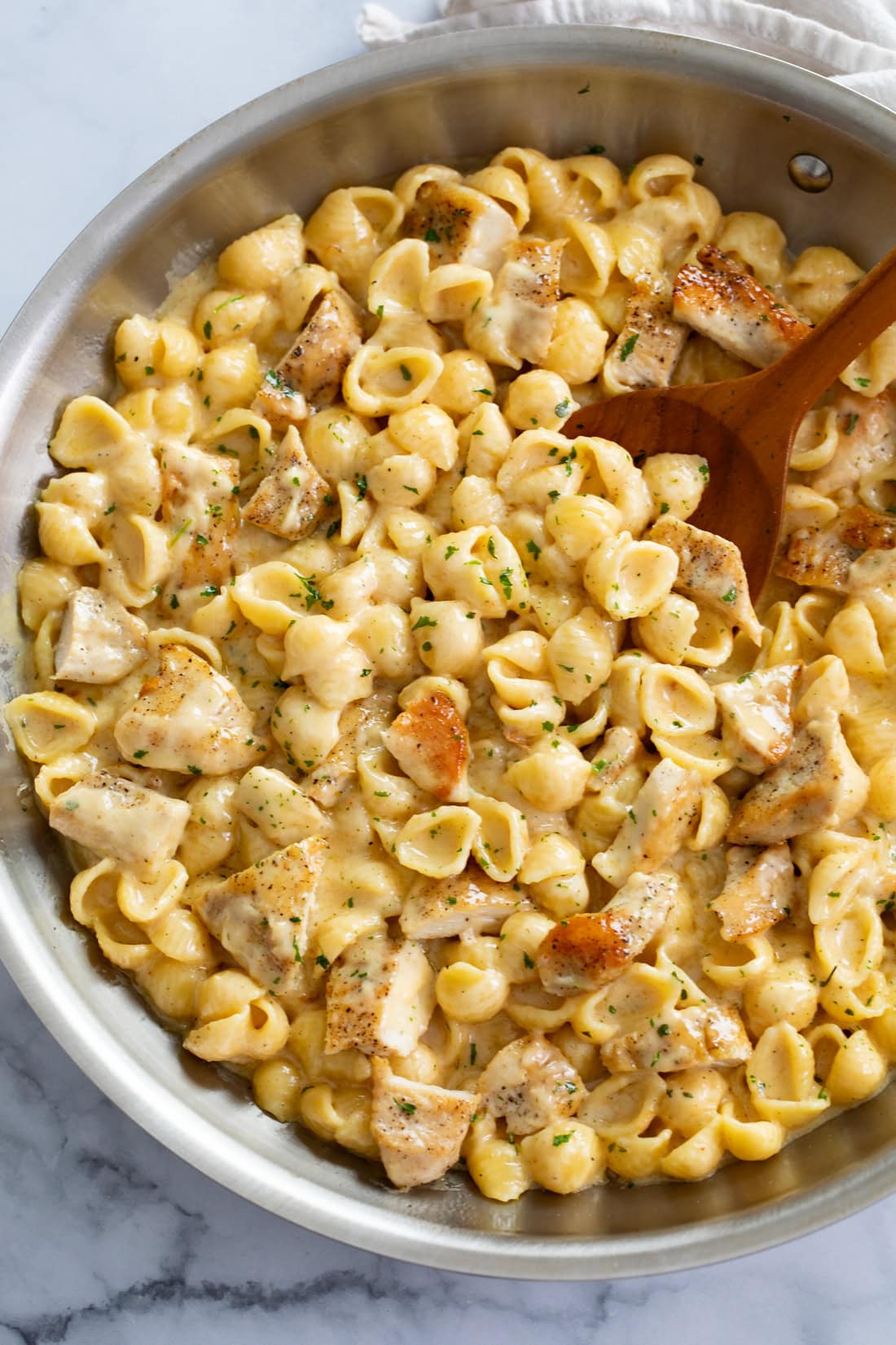 Chicken Mac and Cheese in a skillet with a wooden spoon.