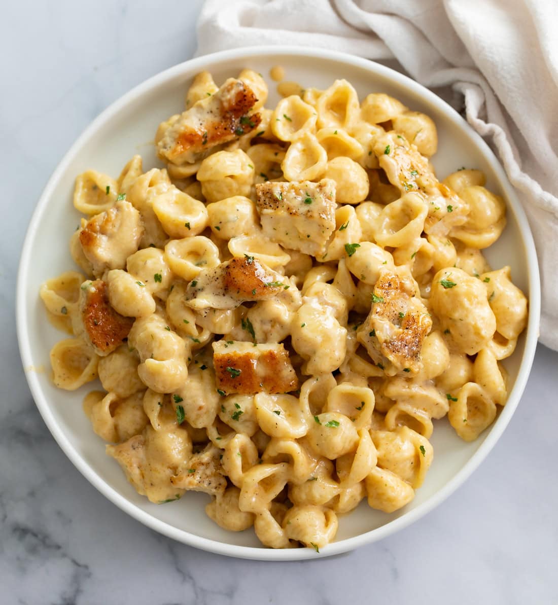 Chicken Mac and Cheese on a white plate with a napkin on the side.