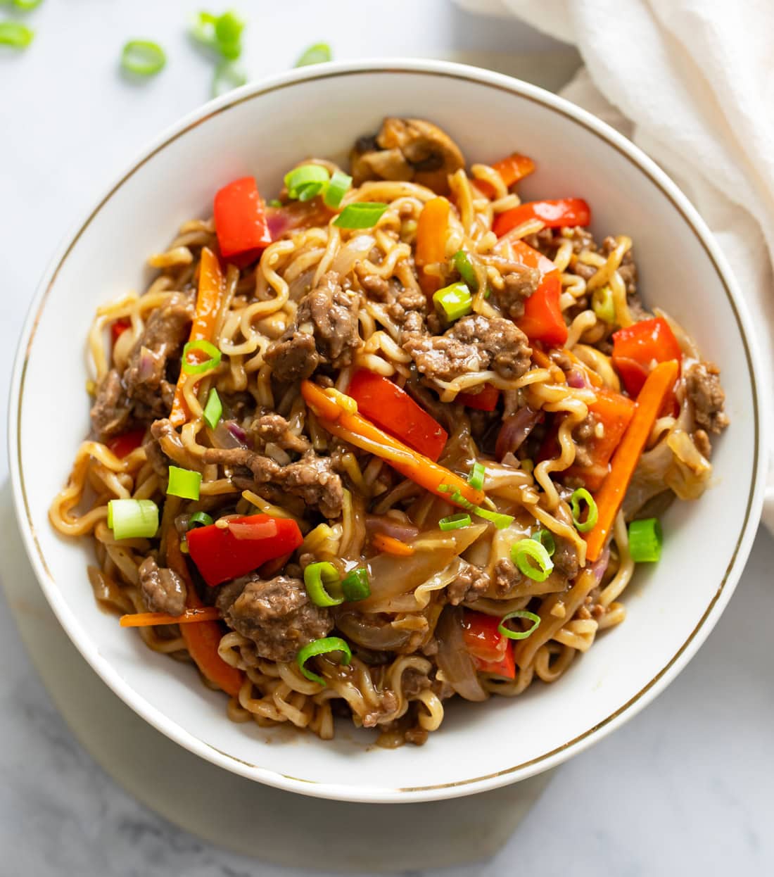 Beef Ramen Noodle Stir Fry in a white bowl with brown sauce and vegetables.