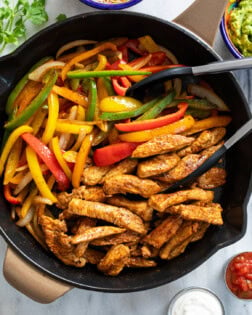 Chicken Fajitas in a skillet with multi-colored bell peppers and strips of seasoned chicken.