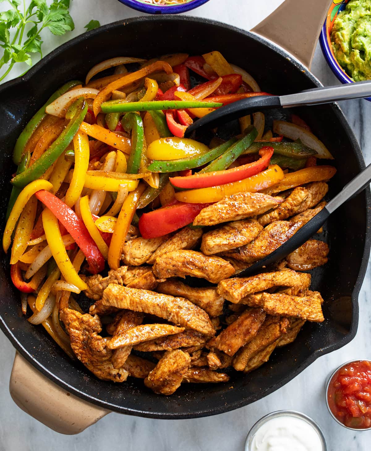 Chicken Fajitas in a skillet with multi-colored bell peppers and strips of seasoned chicken.