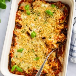 A casserole dish filled with Eggplant Casserole with breadcrumbs and fresh basil on top.