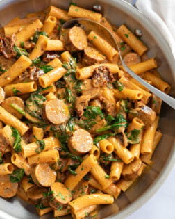 Sun-Dried Tomato Pasta in a skillet with sauce and spinach.