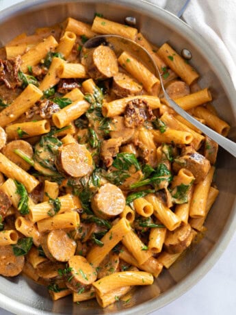 Sun-Dried Tomato Pasta in a skillet with sauce and spinach.