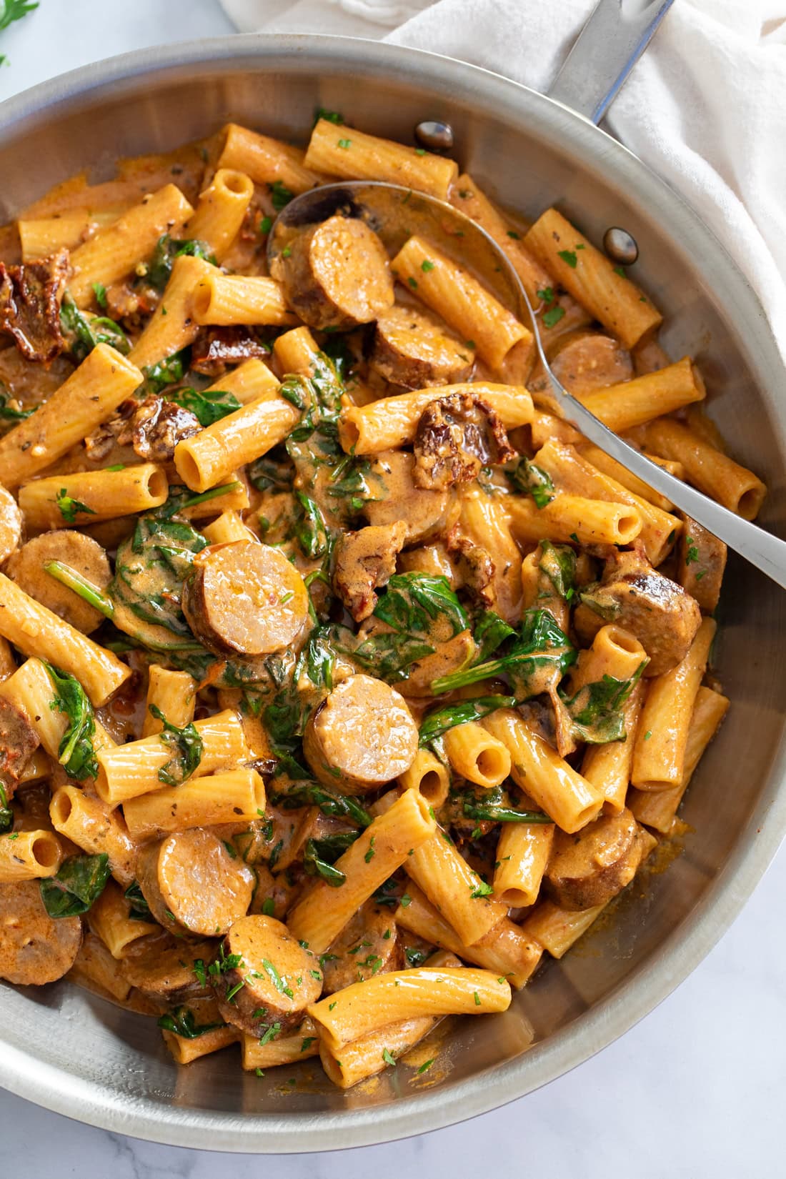 Sun-Dried Tomato Pasta in a skillet with sauce and spinach.