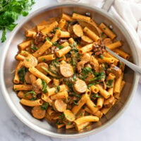 Sun-Dried Tomato Pasta in a skillet with a creamy tomato sauce, spinach, and sausage.