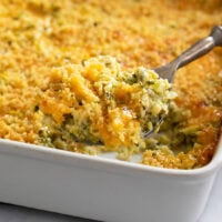 A serving spoon scooping up Zucchini Casserole from a casserole dish.