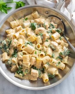 Chicken Spinach Pasta in a stainless steel skillet with a creamy white sauce.