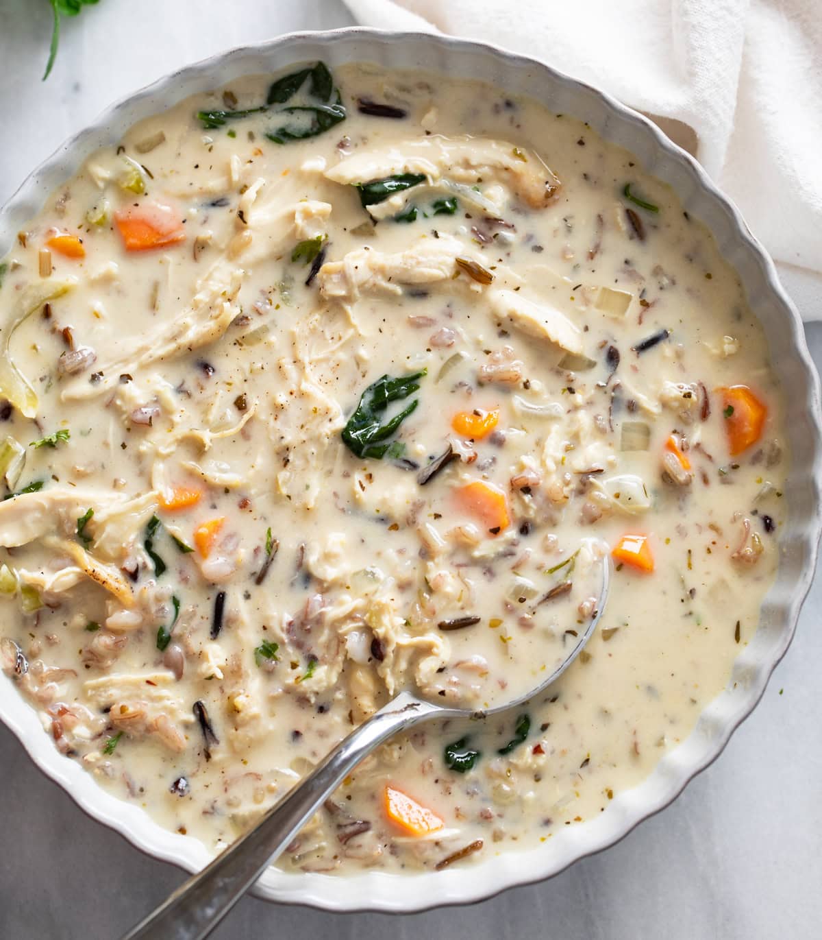 Chicken and Wild Rice Soup in a white serving bowl with a spoon on the side.