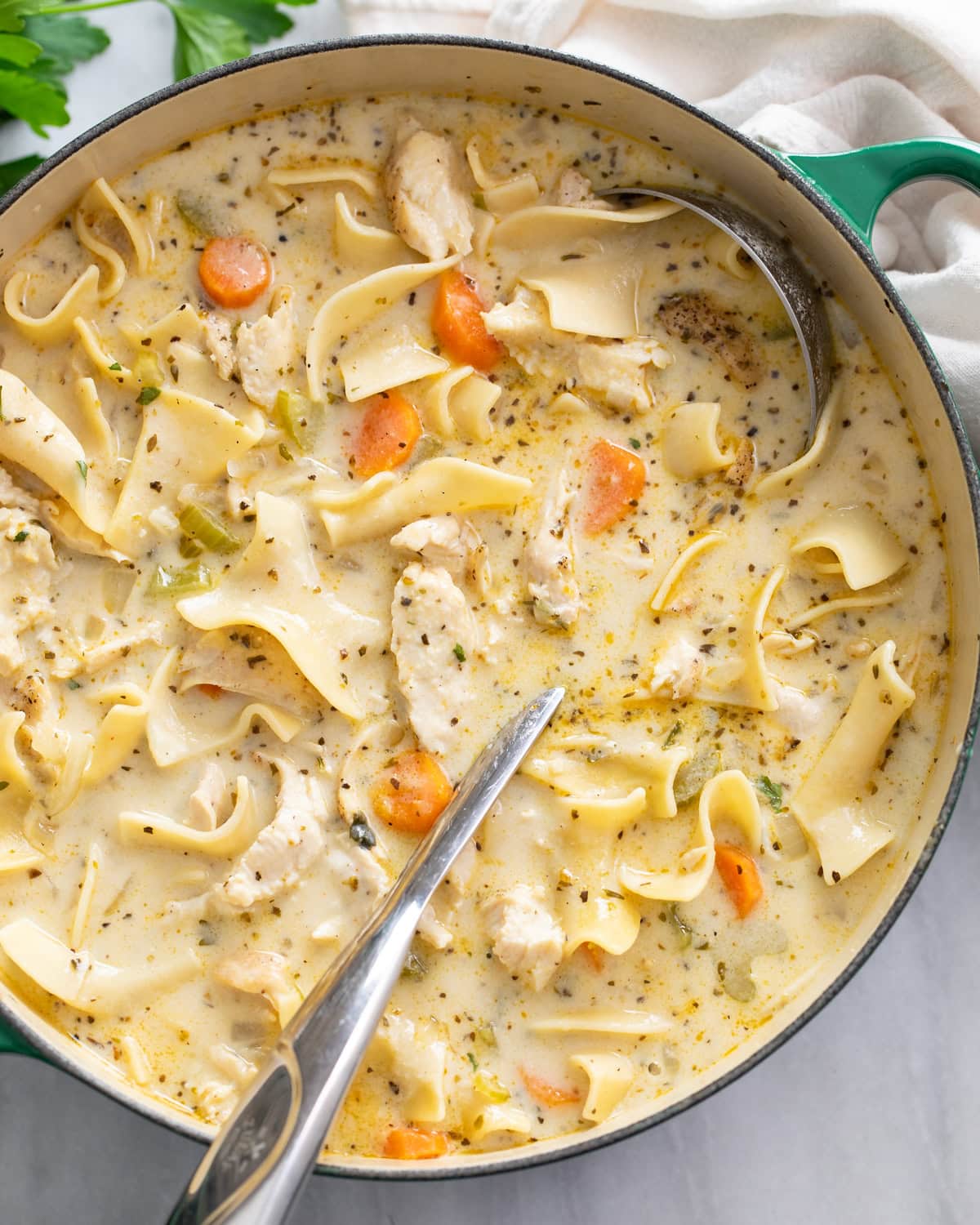 Creamy Chicken Noodle Soup in a soup pot with a soup ladle on the side.